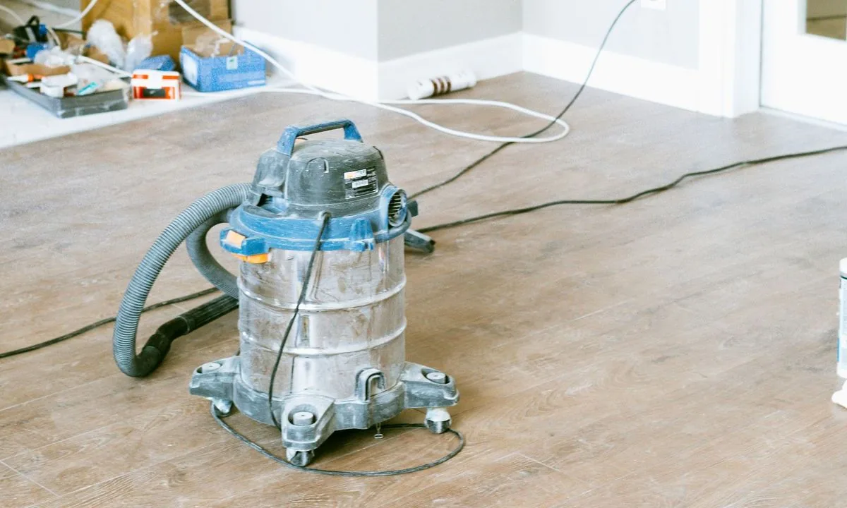 Shop vacuum on the floor of a freshly renovated room, construction dust and cords still down (stock photo)